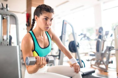 Konsantre sporcumuz spor salonu bankta oturan ve egzersiz halter ile portre çekim sırasında onun pazı çalışma
