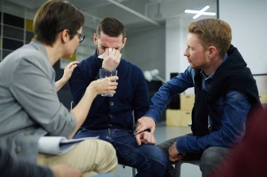 Ağlayan adam psikolojik oturumu sırasında destekleyen arkadaşlar