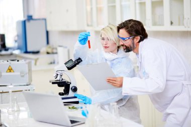 Tüp gururla birlikte yeni kanser aşısı, iç arka plan üzerinde modern laboratuvar oluşturulması üzerinde çalışırken seyir Emanet giyen microbiologists neşeli grup gözlük