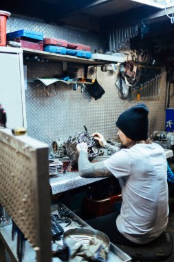 Kırık motor parçaları atölye masada teftiş modern dövmeli adam portresi arkadan görünüm