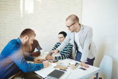 Kendine güvenen iş ortakları tablo Toplantı oturma grubu ve imzalamadan önce yeni sözleşme koşullarını tartışırken, cam duvardan görüntüleyin
