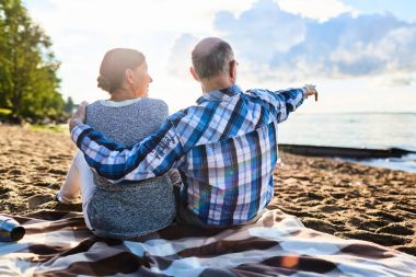 Erkek ve kadın yaz resort kumsalda oturan emekli