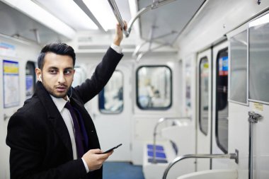 El demiryolu tutarak ve smartphone--dan müzik metro treninin ayakta yakışıklı Ortadoğu işadamı portresi