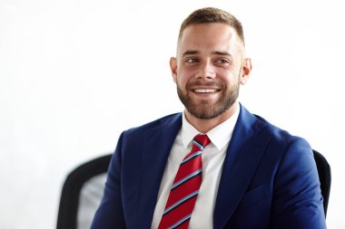 Bel öğe, dikey, sakallı girişimci uzak ofis masa başında otururken dişlek gülümseme ile seyir