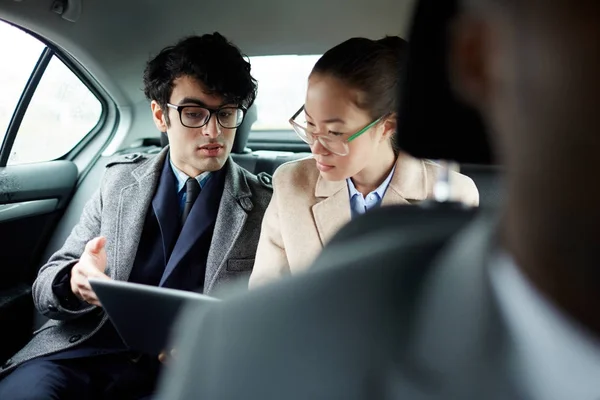 两个成功的商人的肖像骑在车后座 男子和妇女讨论工作文件在出租车 — 图库照片
