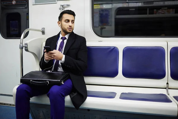 年轻的中东商人的肖像通勤上班在地铁列车 使用智能手机听音乐 — 图库照片