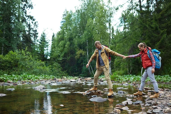 Taş-yol nehir üzerinde geçmek için kız arkadaşı yardımcı genç uzun yürüyüşe çıkan kimse