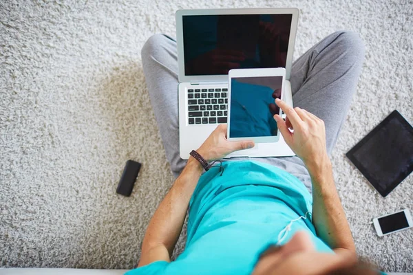 Młody Człowiek Przy Użyciu Tabletu Posiadania Laptopa Kolanach Kiedy Siedzi — Zdjęcie stockowe