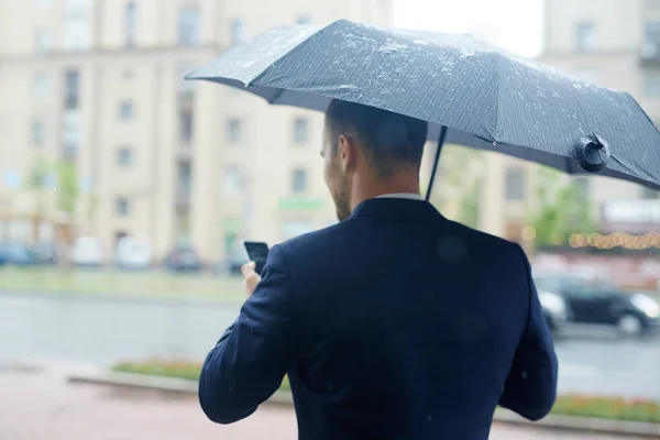 雨の天候でメッセージング忙しい社長の後姿 — ストック写真