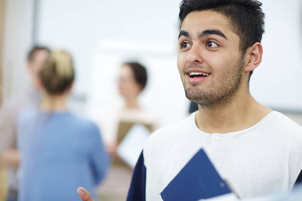 Young specialist listening to colleague with groupmates on background