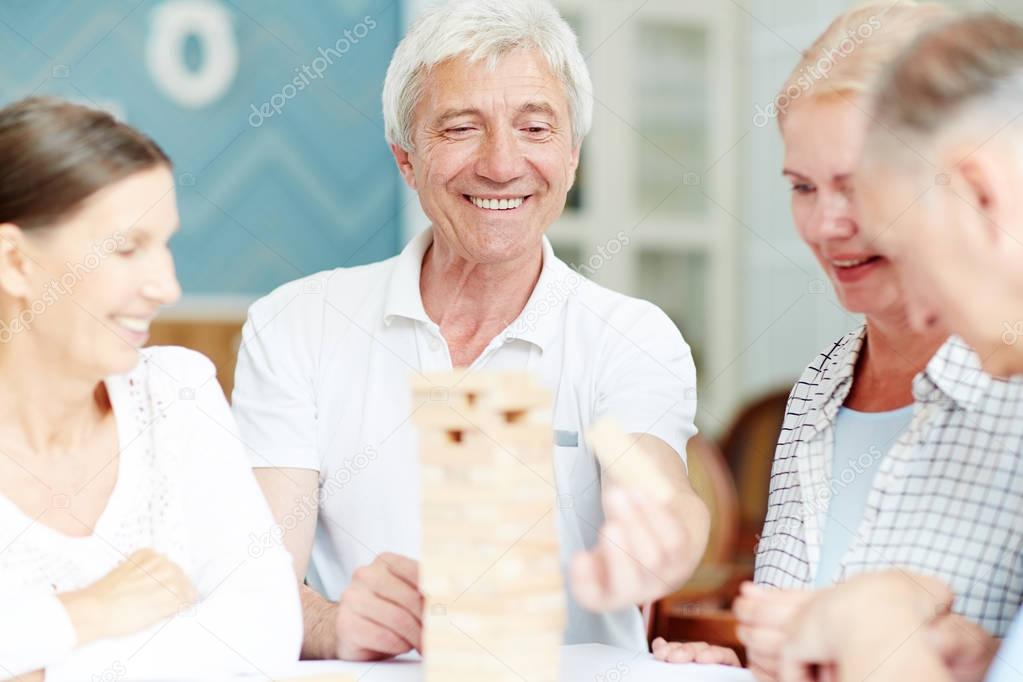 Group of mature friends playing board game during gathering at leisure