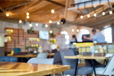 Modern kahvehane iç: rahat sandalyeler, ahşap masa, tanınmayan barista lezzetli kahve, ön plan odaklanarak yapma