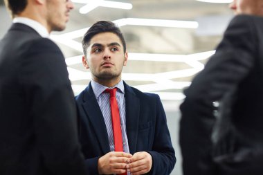 Yakışıklı genç beyaz yakalı işçi ofis lobisinde, düşük açılı görünüş proje tartışma yaparken erkek meslektaşı ilgiyle dinlemeye portre çekim