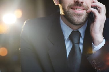 Atış Closeup midsection modern tanınmaz sakallı işadamı smartphone yapma kullanarak ara ve konuşurken gülümseyen