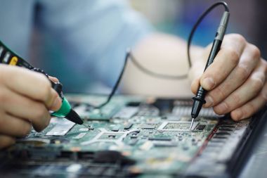 Erkek el elektrik geçerli gerilim devre kartı sökülüp laptop bakım salonu tablo multimetre aracını kullanarak test closeup çekim