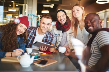 Neşeli arkadaşları proje tartışma ve güzel Cafe, bel-up grup portre geniş gülümsüyor ile fotoğraf için poz dikkati