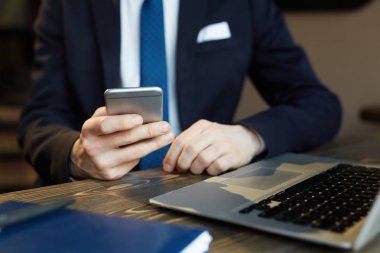 Zarif işadamı dizüstü bilgisayar ve akıllı telefon, çalışma İşyerinde net sörf closeup portresi