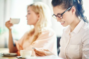 Kafede otururken smartphone manifatura ya da gönüllülük mesaj ile çağdaş genç kadın