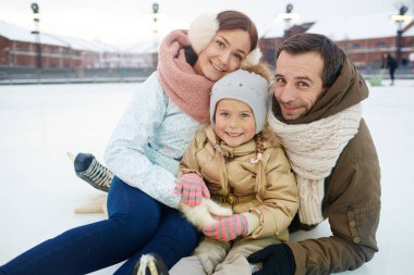 Buz pateni pisti üzerinde oturan winterwear sevgi ve aktif ailede