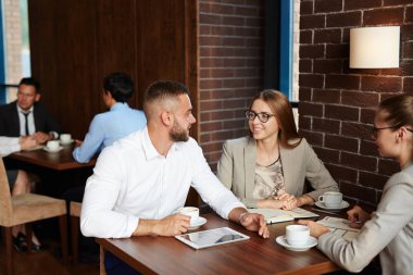 Meşgul restoran öğle vakti iç: beyaz yakalı işçiler animatedly birbirleri ile onların emirleri beklerken sohbet