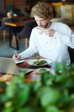 Fincan çay ve kahvaltı dizüstü ekran önünde sahip meşgul manager