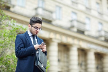 Adam akıllı telefon açık havada sms okuma evrak çantası ile