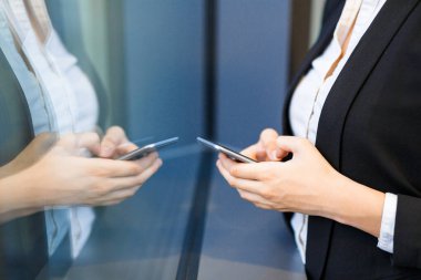 Yakın çekim çekim pencere tarafından dururken smartphone cep telefonu ile Internet tarama tanınmaz ofis çalışanı