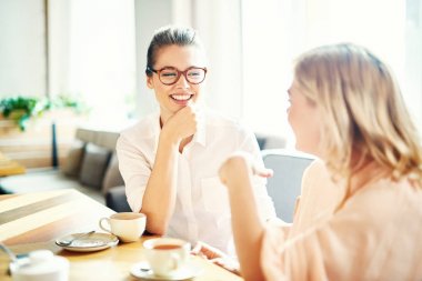 Arkadaşlık güzel anları: neşeli genç kadınlar toplandı birlikte rahat küçük kafede ve animatedly birbirleri ile sohbet