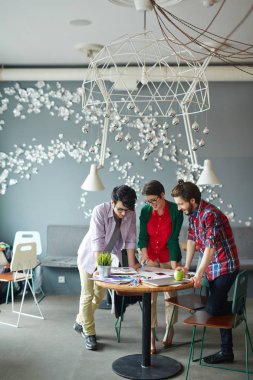 Küçük tablo modern ofis ayakta toplantısında işbirliği rahat kıyafetler giymiş genç yaratıcı kişilik ekip kadeh tam vücut yuvarlak ve kaynağı at arıyorsunuz düzenlendiği