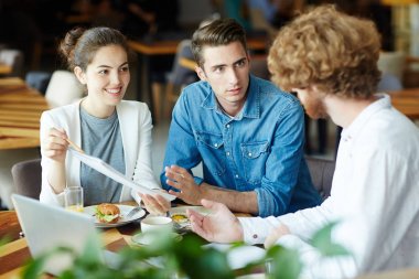 Çok etnik gruptan oluşan grup rahat restoranda toplantı yaparken sakallı, müşterisi için ortak proje ile ilgili fikirleri sunan yetenekli iç tasarımcılar