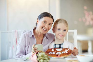 Mutlu büyükanne ve torunu ile ev yapımı pasta çay içiyor