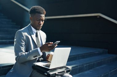 Dizüstü bilgisayar ve smartphone sokakta merdivenlerde oturan işadamı