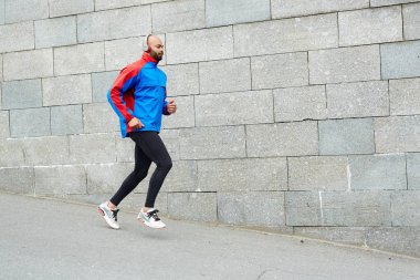 Etkin adam şehir duvar boyunca çalışan kulaklıklar ile