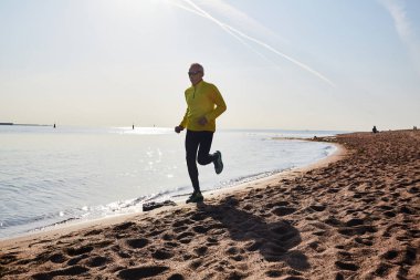 Deniz kıyısı açık eğitim, ısmarlayarak arka plan üzerinde yaparken koşan sportif yaşlı adam
