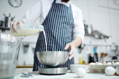 Baker üniformalı plastik şişe süt kasenin içine dökme