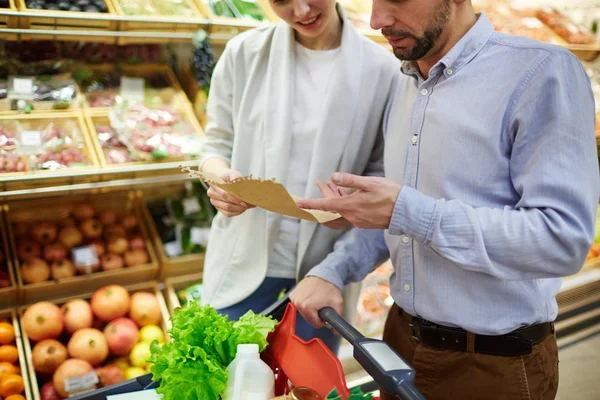 Junges Ehepaar Diskutiert Einkaufsliste Supermarkt — Stockfoto