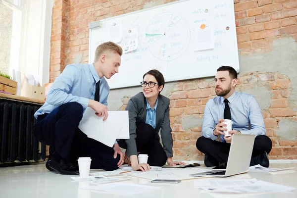 Squadra Giovani Professionisti Discutere Documenti Sul Pavimento — Foto Stock