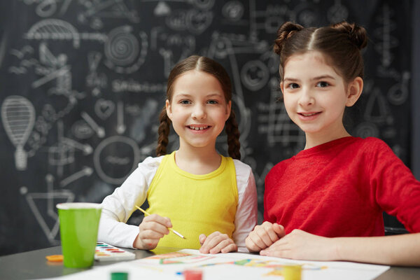 Small group of schoolgirls looking at camera at lesson of drawing