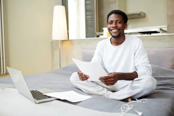 로터스 위치에 침대에 앉아서 서류를 미소로 카메라를 즐거운 아프리카계 미국인 — 스톡 사진