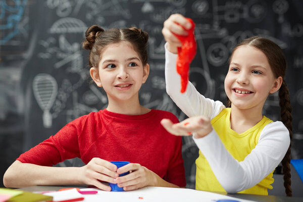 Playful girl having fun with red slime while her friend looking at this