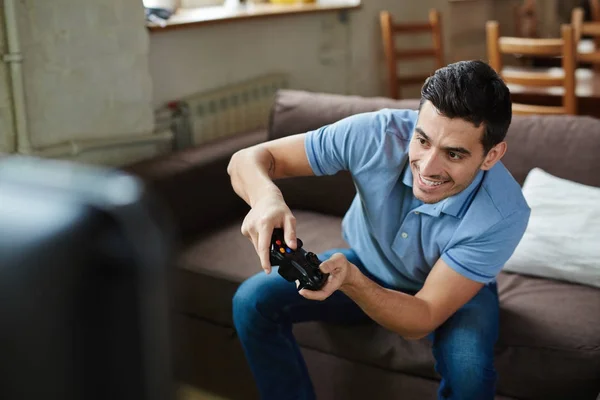 高角度肖像英俊的情感成人玩视频游戏手持无线控制器和微笑快乐 而坐在沙发上在家 — 图库照片