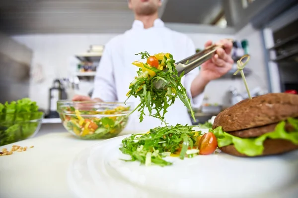 厨师在盘子里放新鲜蔬菜沙拉给客户 — 图库照片