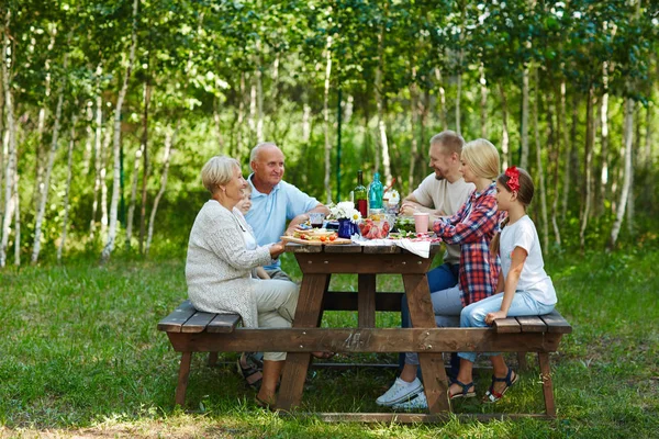家族は 自然環境で木製のテーブルで座って — ストック写真