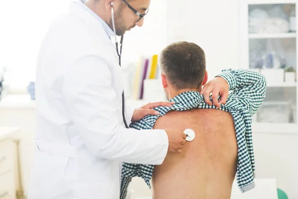 Visão Traseira Paciente Sentado Enquanto Médico Examina Com Estetoscópio — Fotografia de Stock