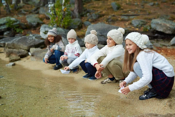 Grupo Crianças Felizes Sentadas Margem Lago Por Água Limpa Brincando — Fotografia de Stock