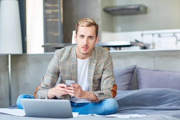 Unga Hem Kontorist Med Smartphone Textilen Framför Laptop Medan Sitter — Stockfoto