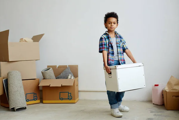Calm boy holding packed box while looking at camera