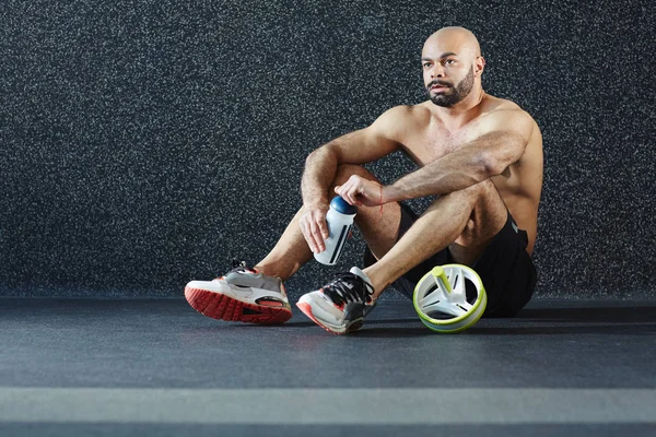 Shirtless Chlap Lahví Vody Sedí Podlaze Tělocvičny — Stock fotografie