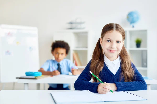 可爱的女孩与蜡笔坐在办公桌与同学的背景 — 图库照片