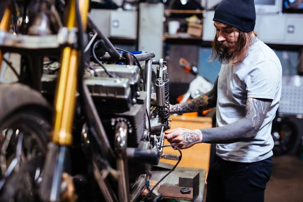 Getatoeëerd motorfiets monteur montage in Garage — Stockfoto